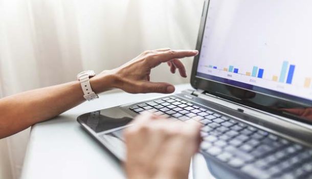 A person focused on typing on a laptop computer, with hands positioned over the keyboard.