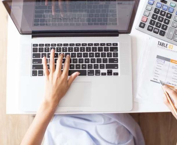 A woman in a business suit is focused on her laptop, working diligently in a professional setting.  