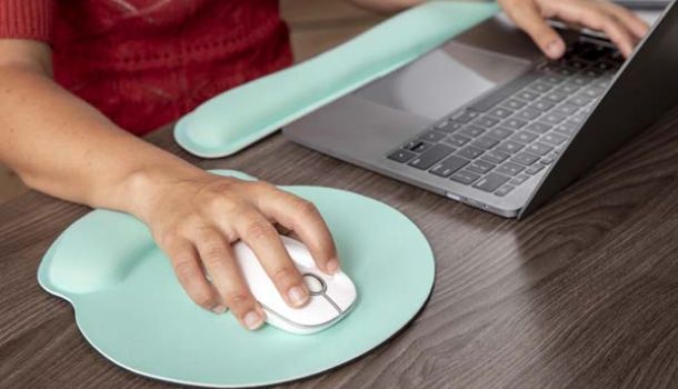 A person focused on typing on a laptop computer, with hands positioned over the keyboard.