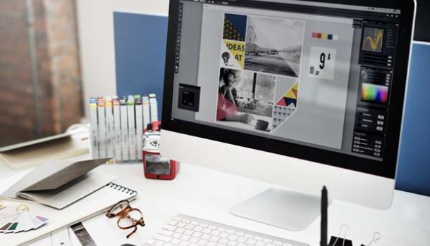A desktop computer setup featuring a monitor, mouse, keyboard. The monitor displays website design software 