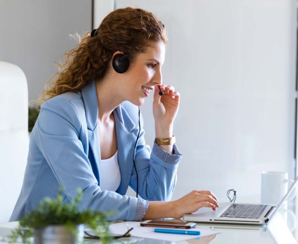 A woman in a business suit is focused on her laptop, working diligently in a professional setting.  
