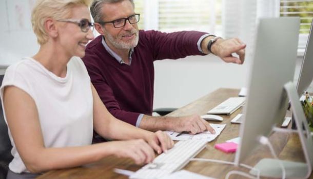  A man and woman collaborate on a computer, focused on their work in a modern office setting.  