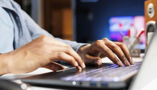  A person focused on typing on a laptop computer, with hands positioned over the keyboard.