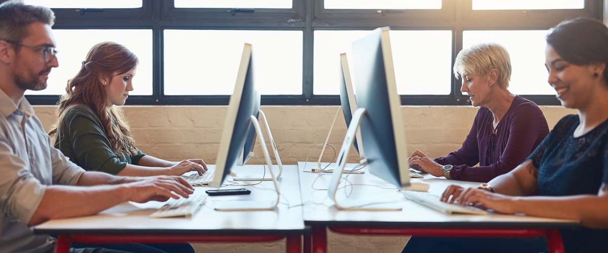 A group of diverse individuals engaged in discussion around a conference table in a modern office setting.