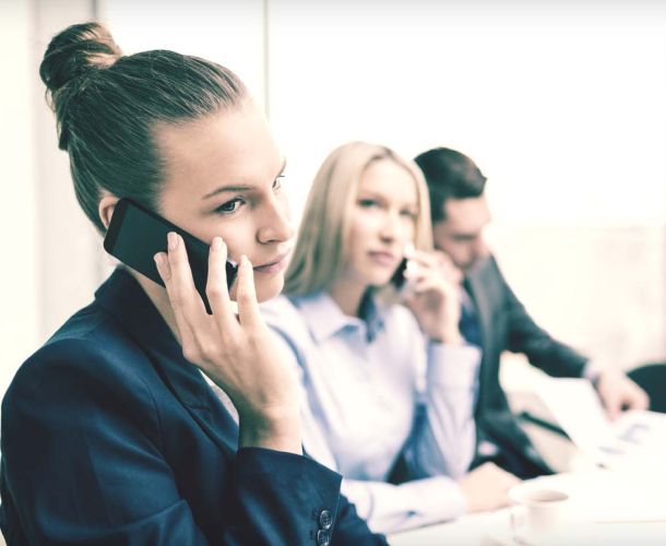 A group of diverse individuals engaged in discussion around a conference table in a modern office setting.