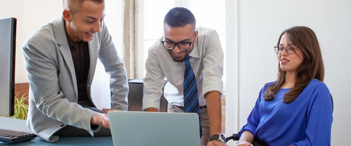 A group of diverse individuals engaged in discussion around a conference table in a modern office setting.