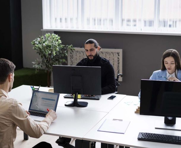 A group of diverse individuals engaged in discussion around a conference table in a modern office setting.