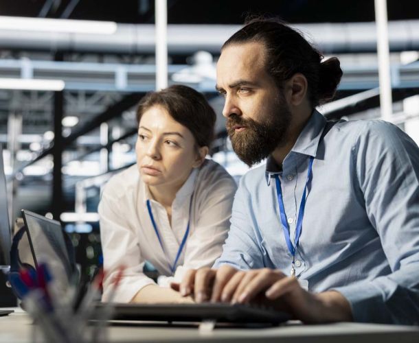 A woman in a business suit is focused on her laptop, working diligently in a professional setting.  