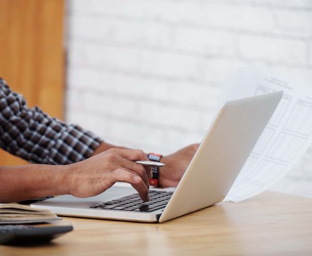 A person focused on typing on a laptop computer, with hands positioned over the keyboard.  