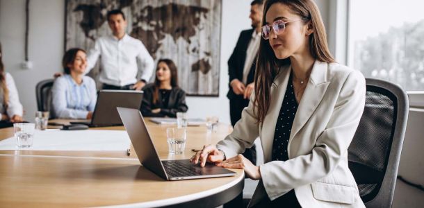 A woman in a business suit is focused on her laptop, working diligently in a professional setting.  
